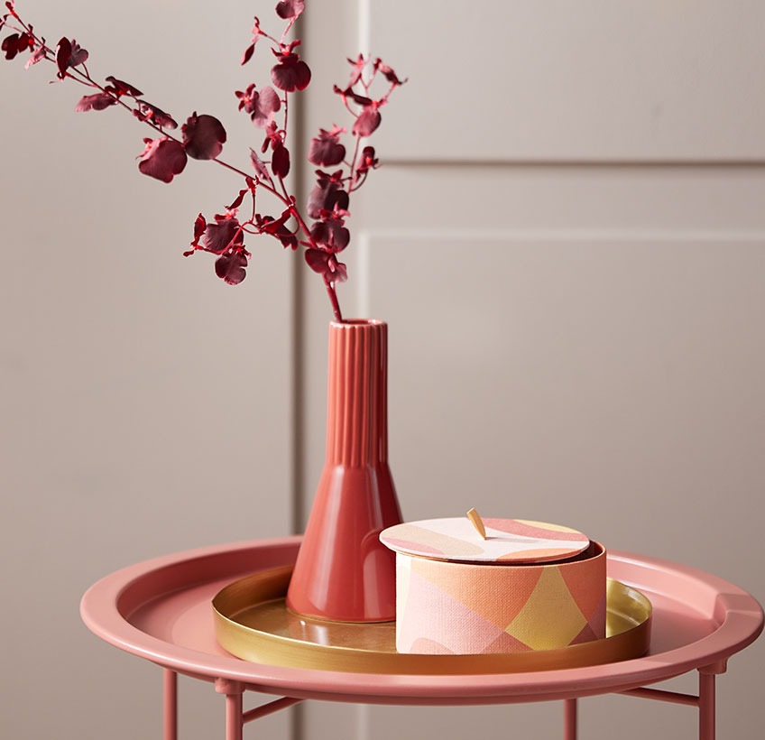 Red vase and round storage box on a brass coloured decorative tray 