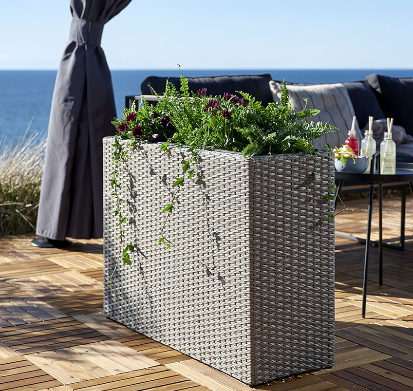 Hoge tuinplanter op een houten terras 