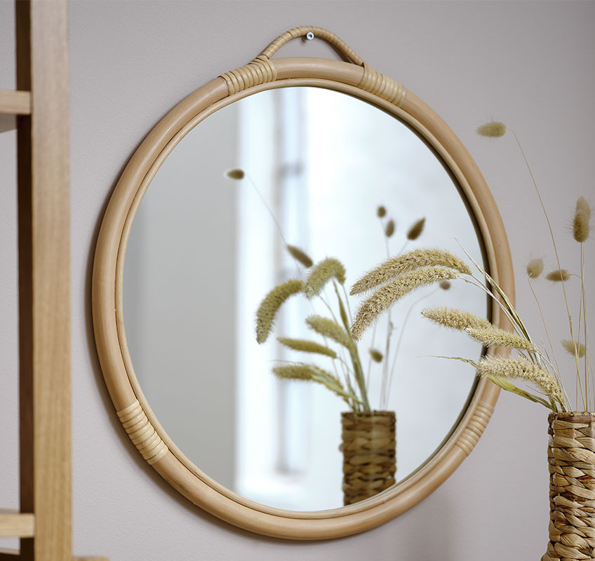 Ronde rotan spiegel tegen beige muur