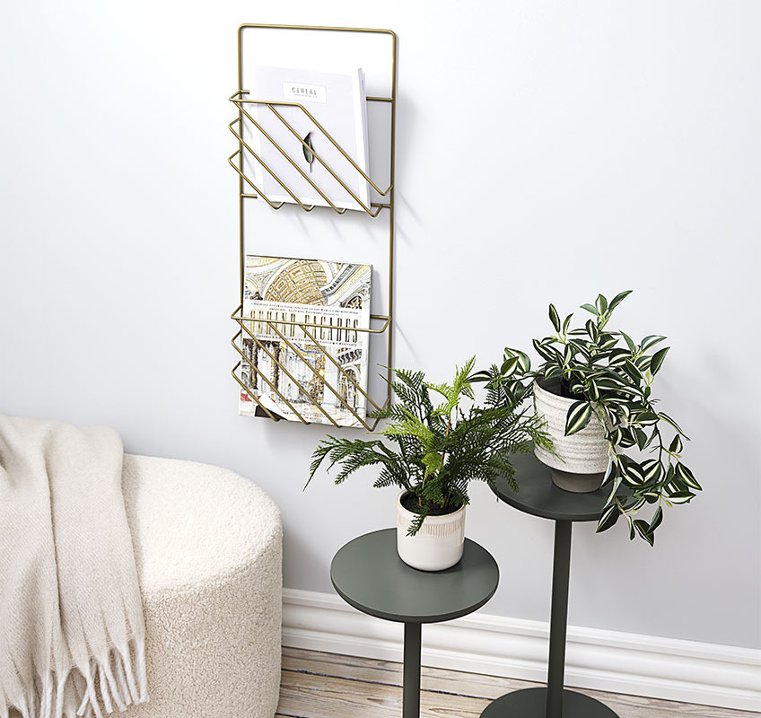 STAND IN plantenstandaard en MAGSTRUP tijdschrifthouder in goud Twee plantenstandaarden in groen en gouden tijdschrifthouder aan de muur
