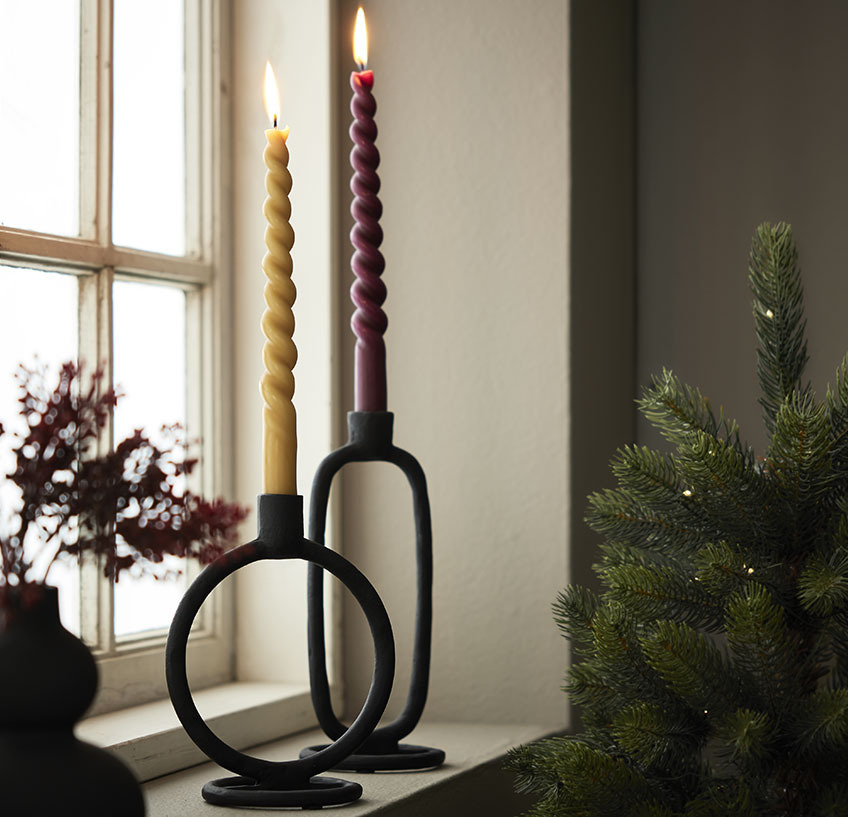 Windowsill with twisted candles in black candlesticks 