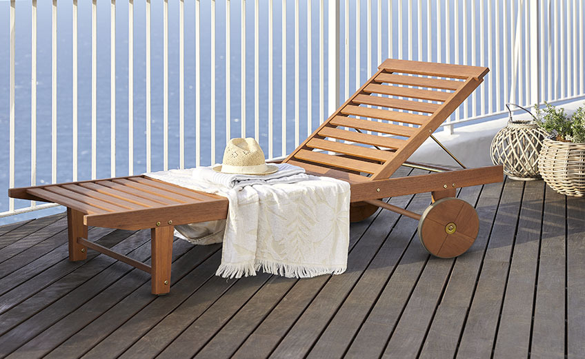 Bain de soleil en bois à roulettes sur un balcon au bord de l'océan