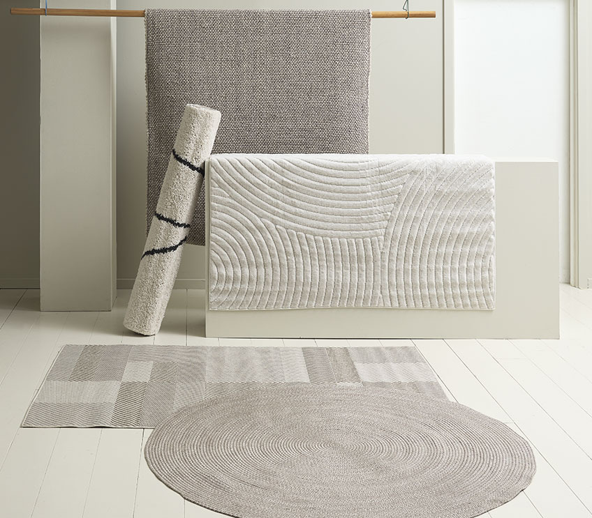 Tapis rond d’intérieur MASKROS au-dessus du tapis carré LONAS. Tapis SANDFIOL couleur crème suspendu devant le tapis gris/brun AVENBOK Tapis d’intérieur rond devant des tapis rectangulaires dans différentes couleurs naturelles